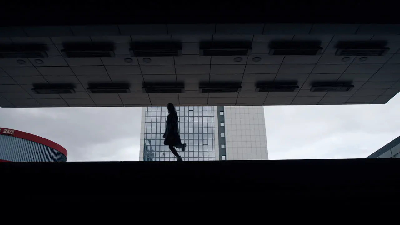 Silhouette female person jumping in dark underground station or parking