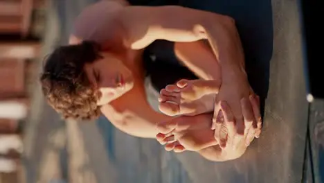 A young brunette guy in black shorts is stretching on a sunny beach Close up shot of a young guy doing morning exercises