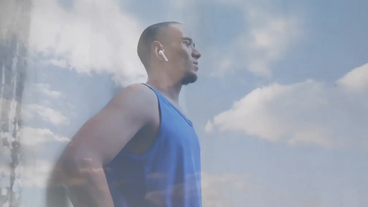 Animation of clouds over male athlete using wireless earphones and smartwatch exercising outdoors