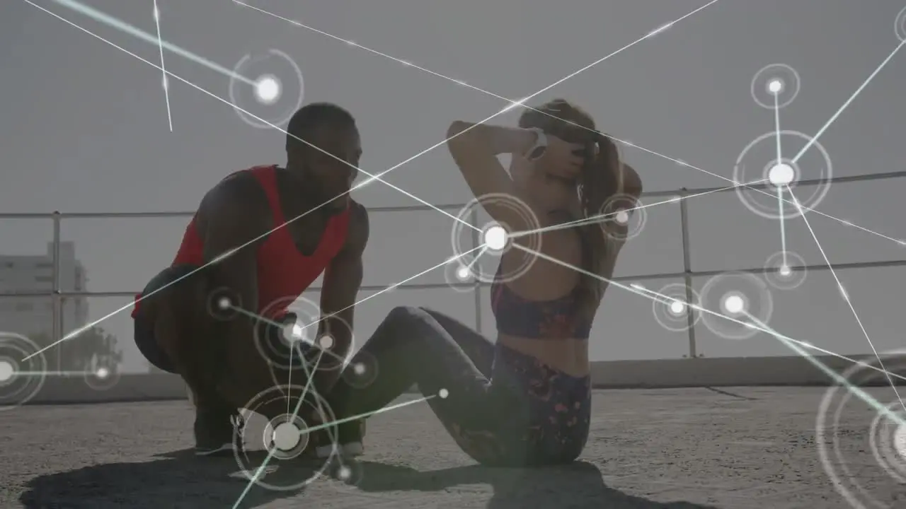 Network of connections against mixed race couple performing abs exercise together on the promenade