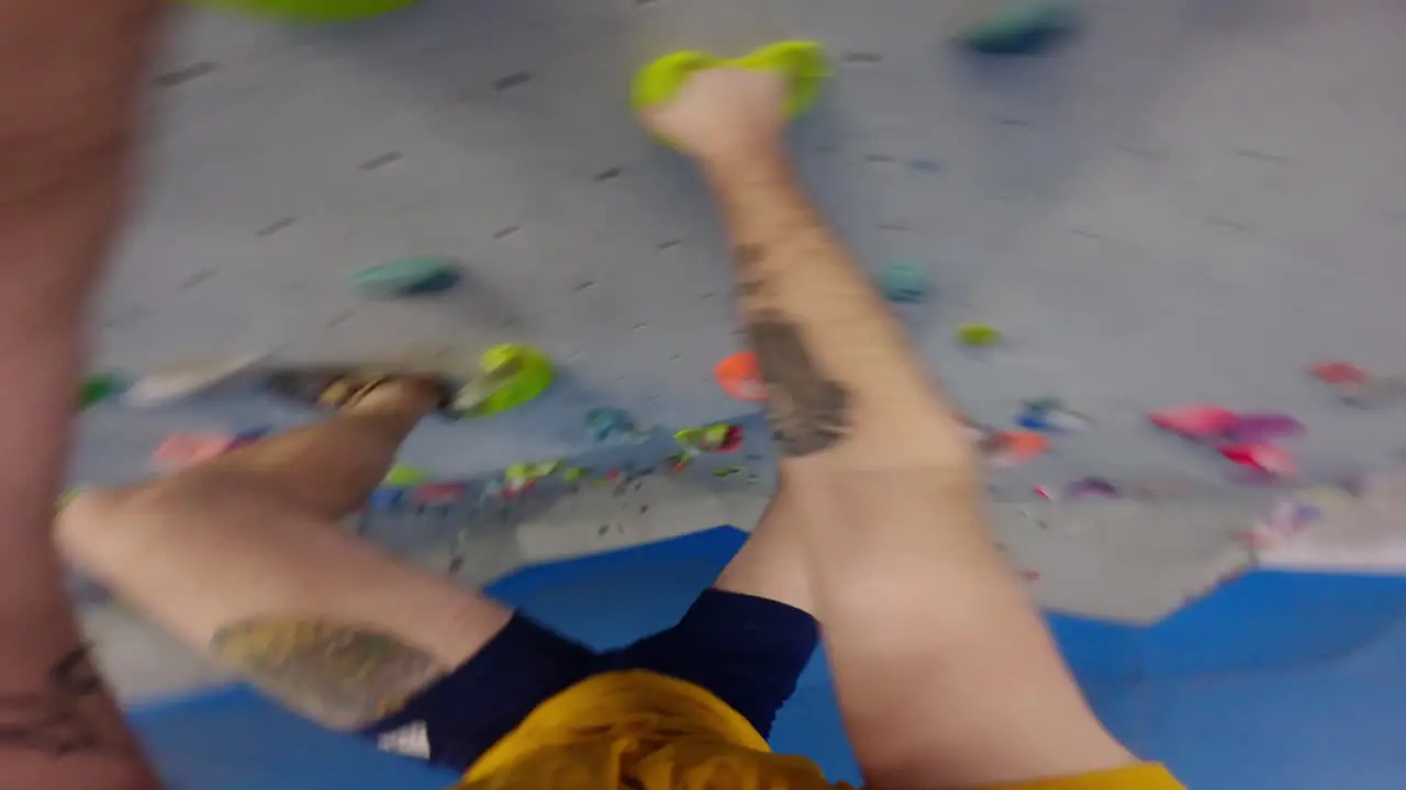 POV shot of a climber man with tattoos climbing in a bouldering gym an overhang wall