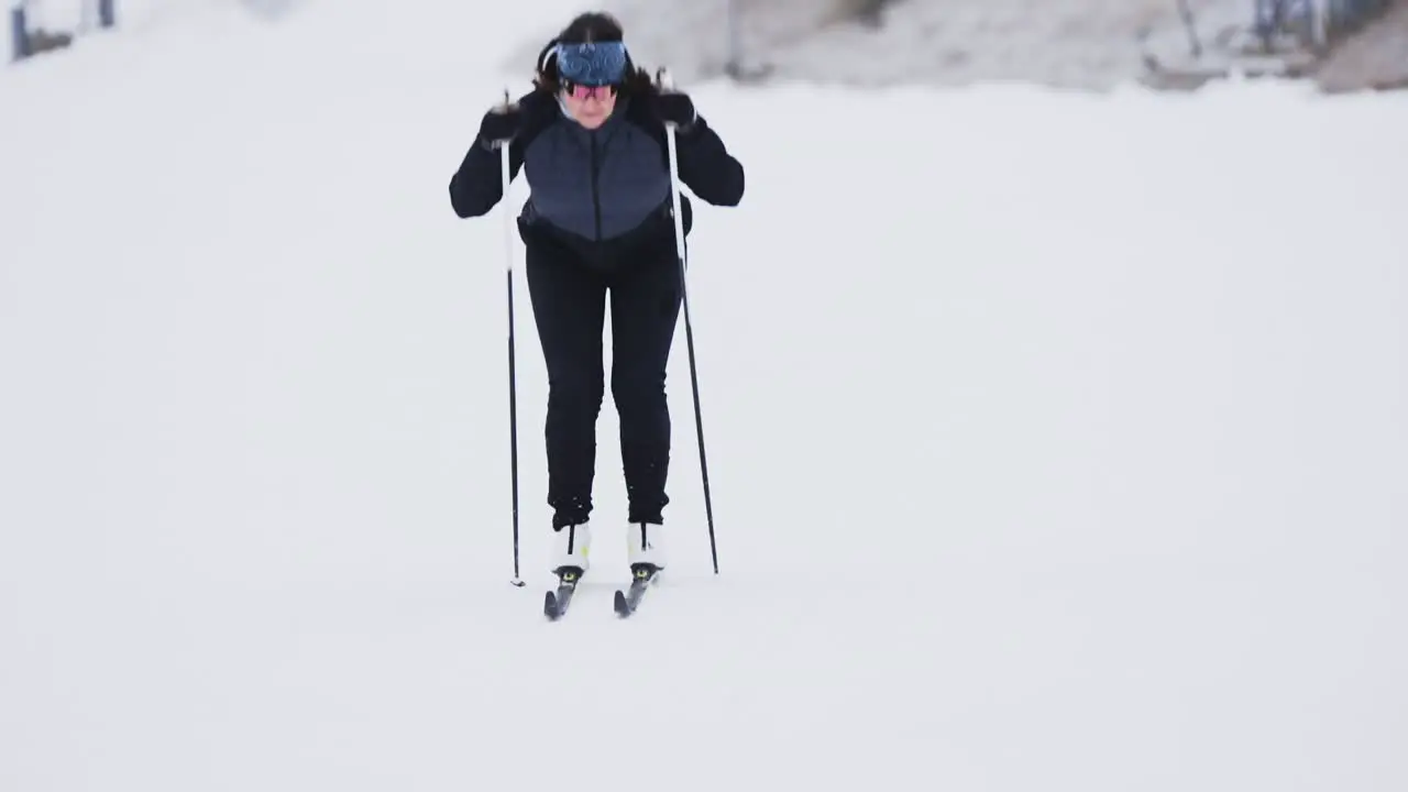 Dramatic zoomed in shot of female skiier passing camera in slow motion