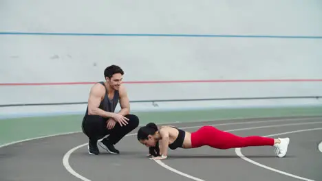 Couple training together on track Man and woman warming up at stadium