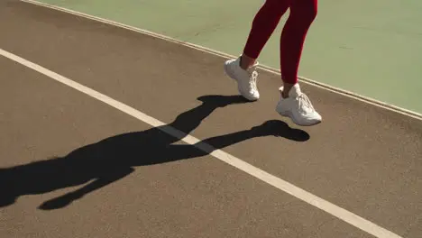 Closeup female feet jogging in trainers on track Girl running outdoors on track