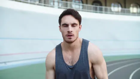 Portrait of exhausted man training at modern stadium Young man runner