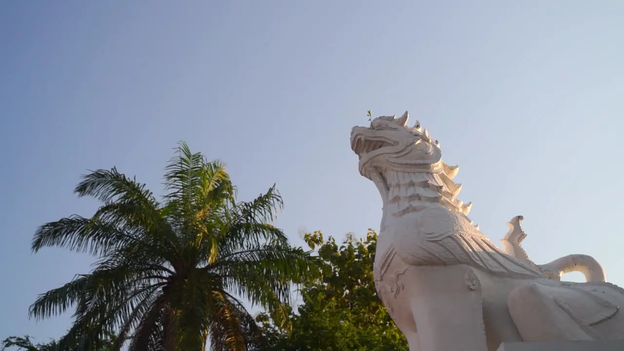 Slow motion rotating shot over temple Lion statue looking up at blue sky