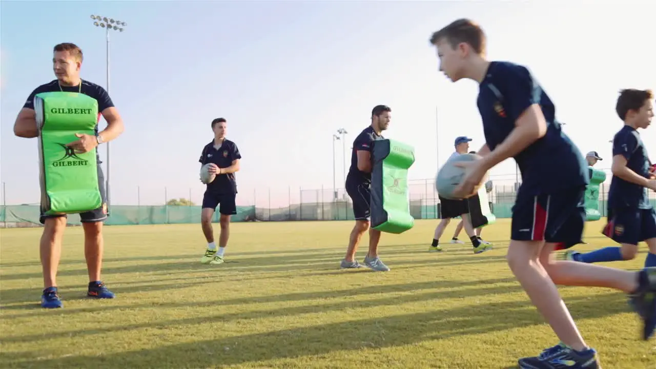 Young Rugby Players At The Field During Workout Training With Their Coaches low angle full shot