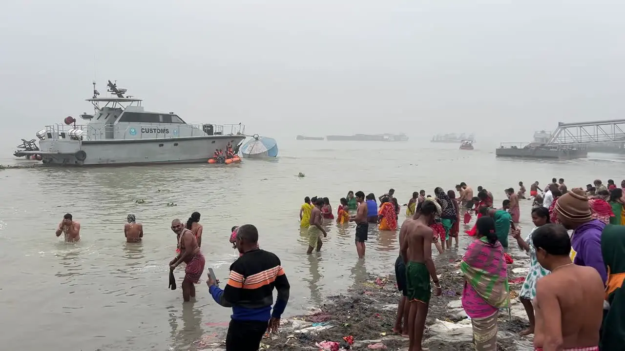 Rear view of People bathing and praying during Sankranti near a jetty in Babughat Kolkata during sunset