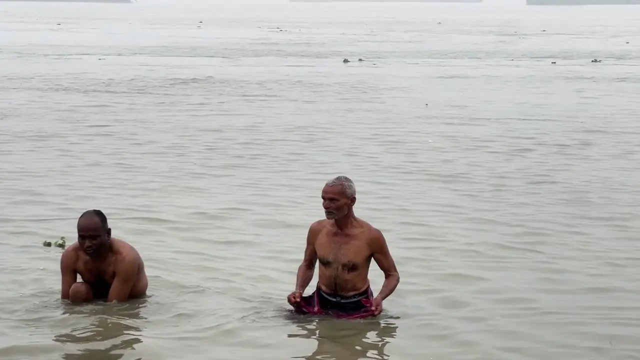 Front view of men talking the holy dip and praying in foggy winter morning during Sankranti with seascape at background in Babughat Kolkata