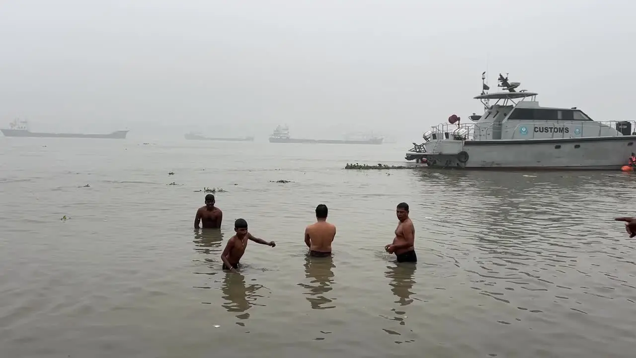 Rear view of few men and boys bathing and offering prayers during a cloudy evening in Babu Ghat Kolkata