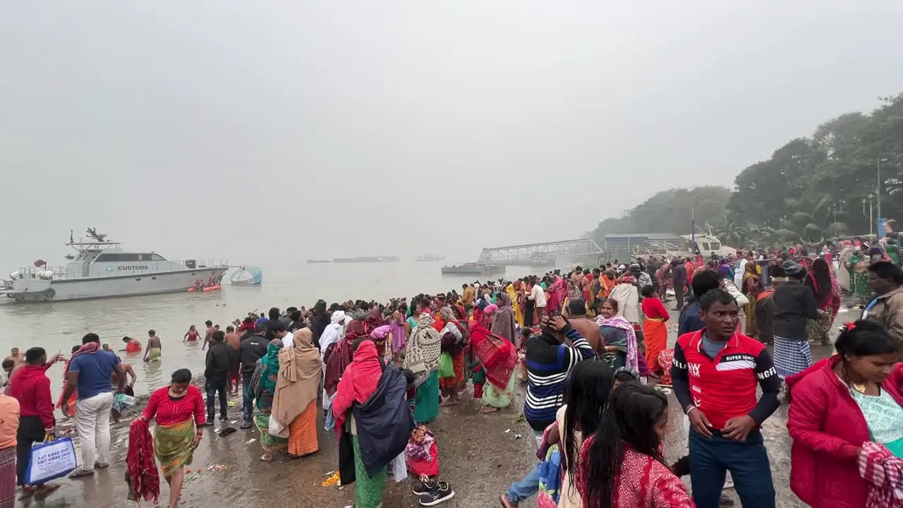 Wide shot of Hindus taking religious bath in Babughat Kolkata for the celebration of Sankranti festival during evening