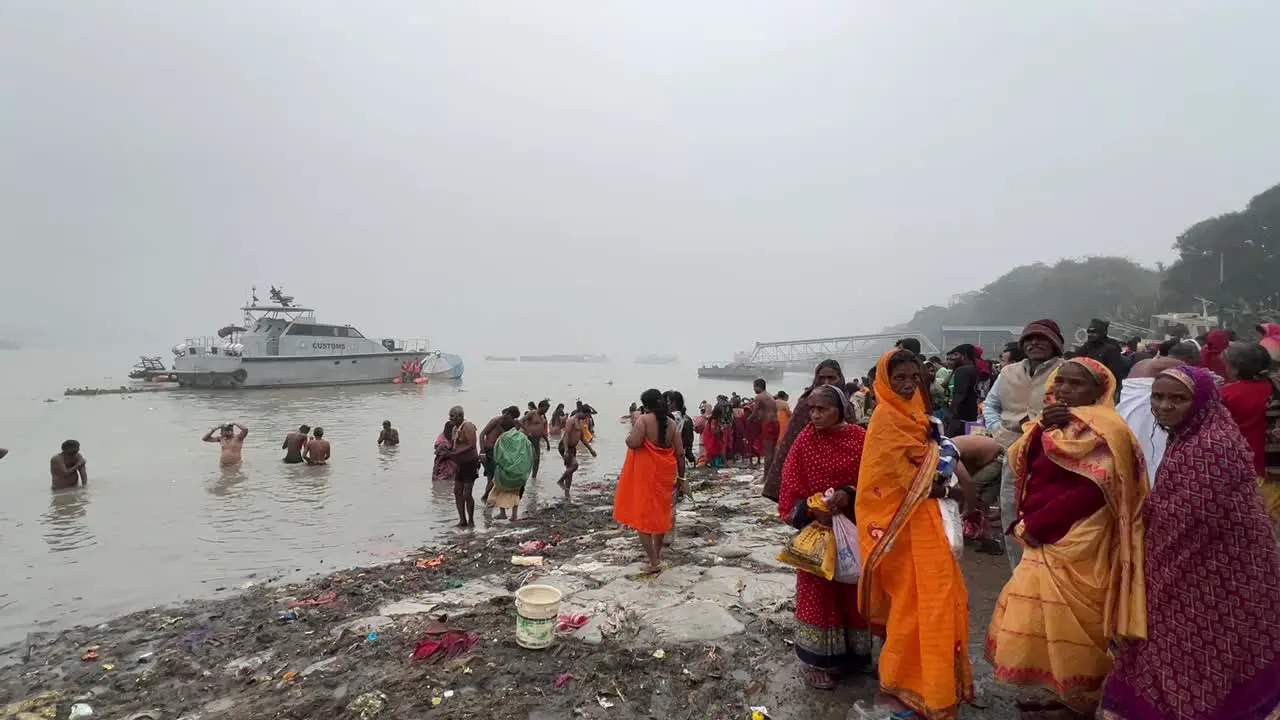 Wide shot of Hindus bathing in Babu ghat Kolkata for the celebration of Sankranti festival during cloudy evening in India