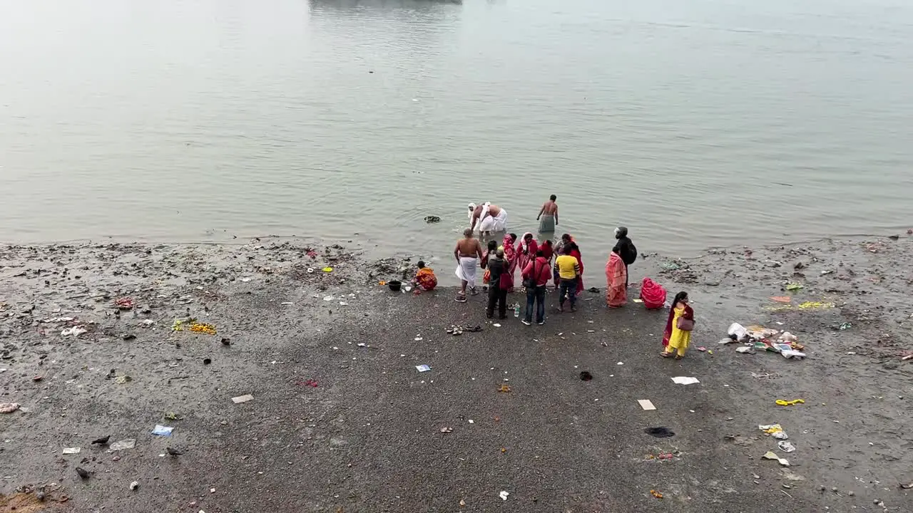 Wide shot of people bathing and offering prayers to god near Hooghly river during evening in Kolkata India