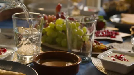 Muslim Family Table At Home Set For Iftar Meal Breaking Daily Fast During Ramadan With Water Being Poured