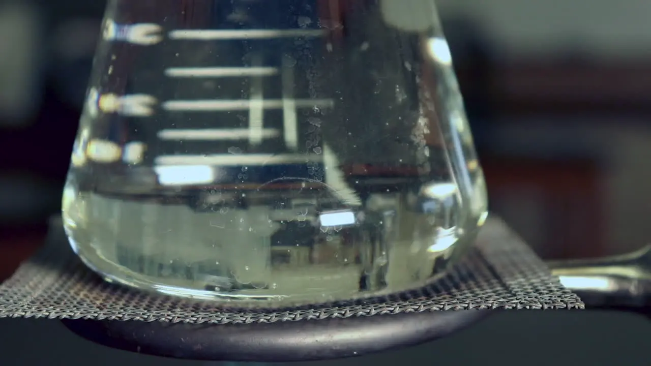 CLOSE UP Erlenmyer Flask that is being heated by a bunsen burners no condensation left heat waves visible in flask bubbles rapidly forming