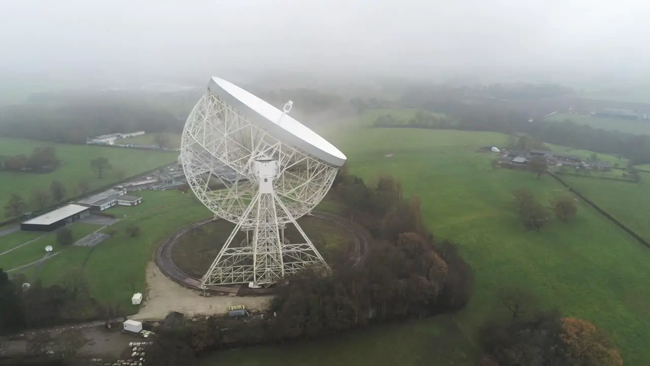 Aerial Jodrell bank observatory Lovell telescope misty rural countryside slow descend side view