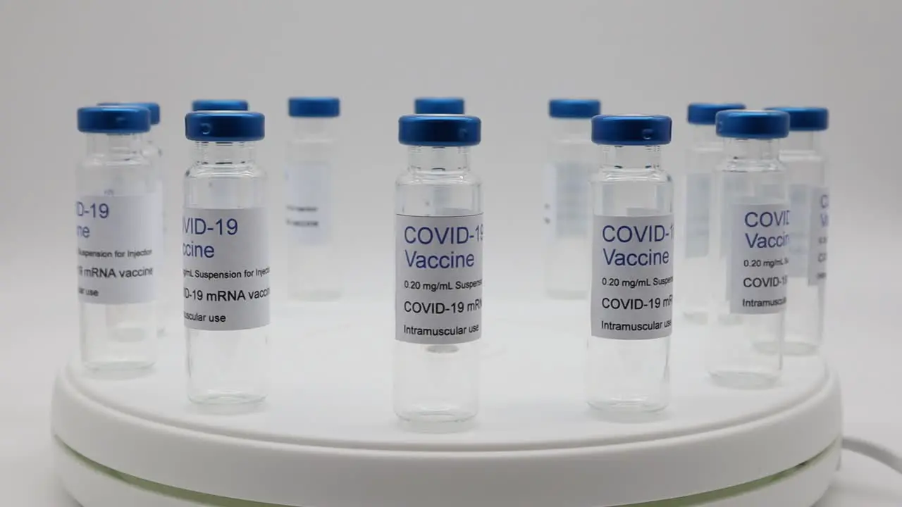 Transparent empty glass vials with Covid-19 Vaccine label on rotating display