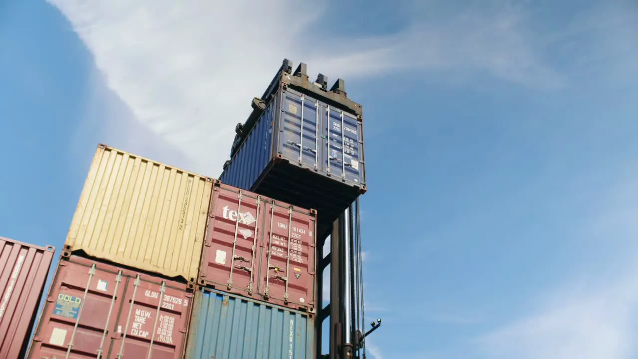 Forklift carefully stacking heavy shipping container in Port of Montreal storage dockyard