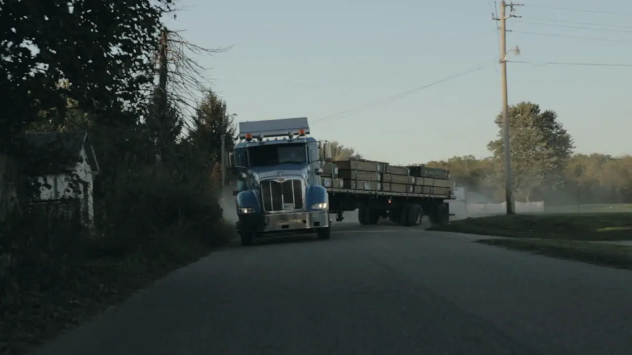 Peterbilt semi truck pulling out of yard and driving down the street front view