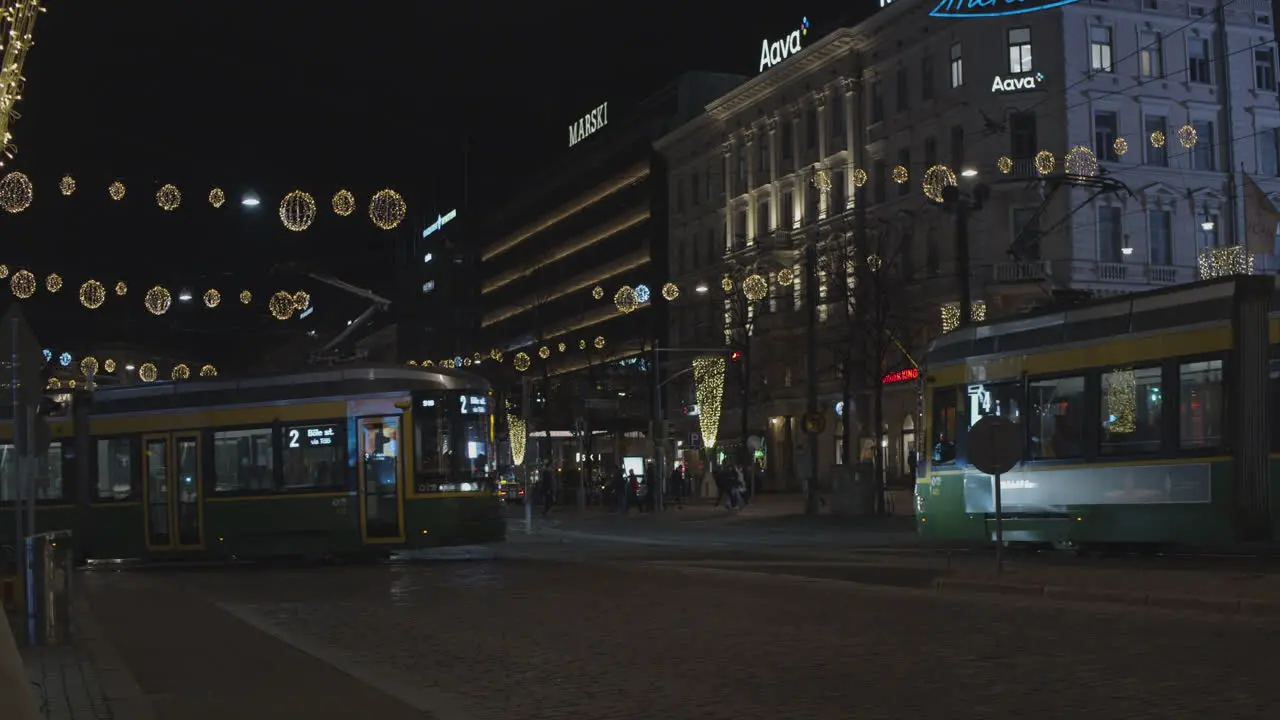 Three trams pass on a street decorated with Christmas lights at night