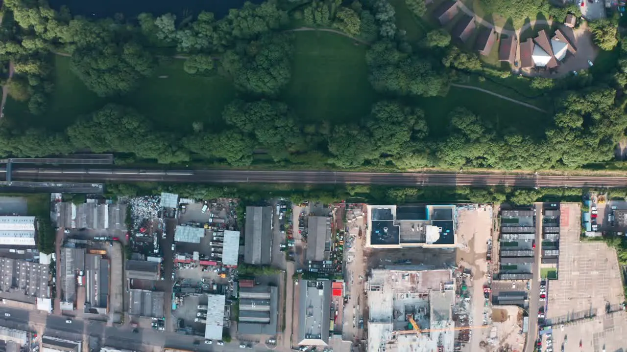 top down drone shot of train passing between nature and built up scrap yard