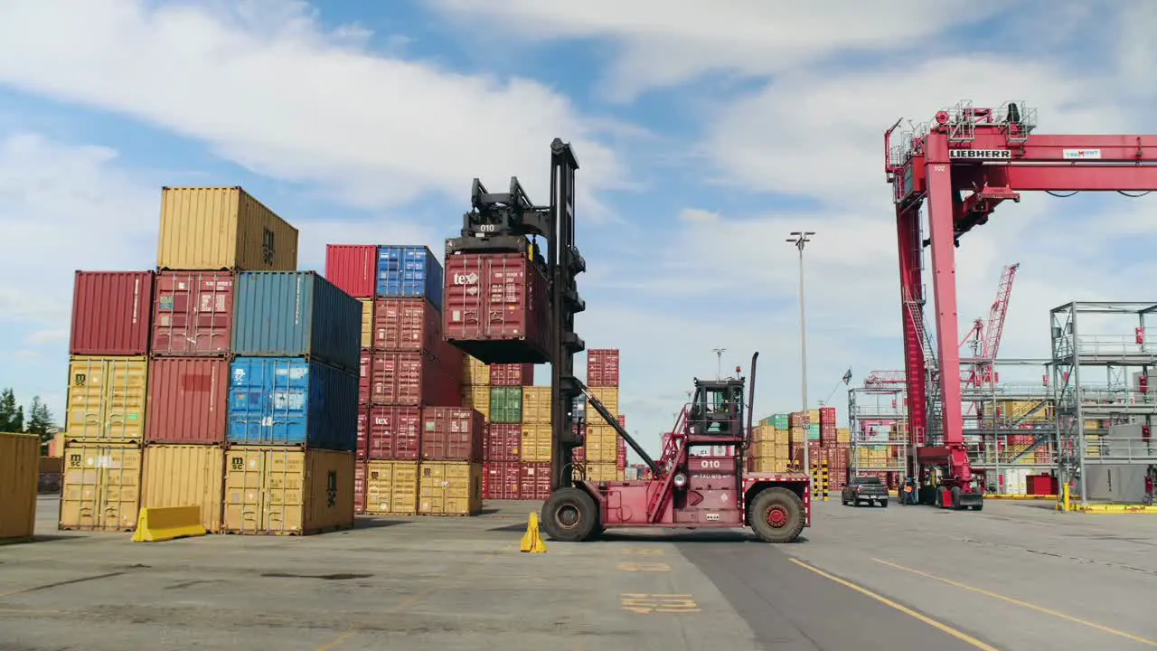 Forklift truck stacking heavy shipping container in Port of Montreal dockyard