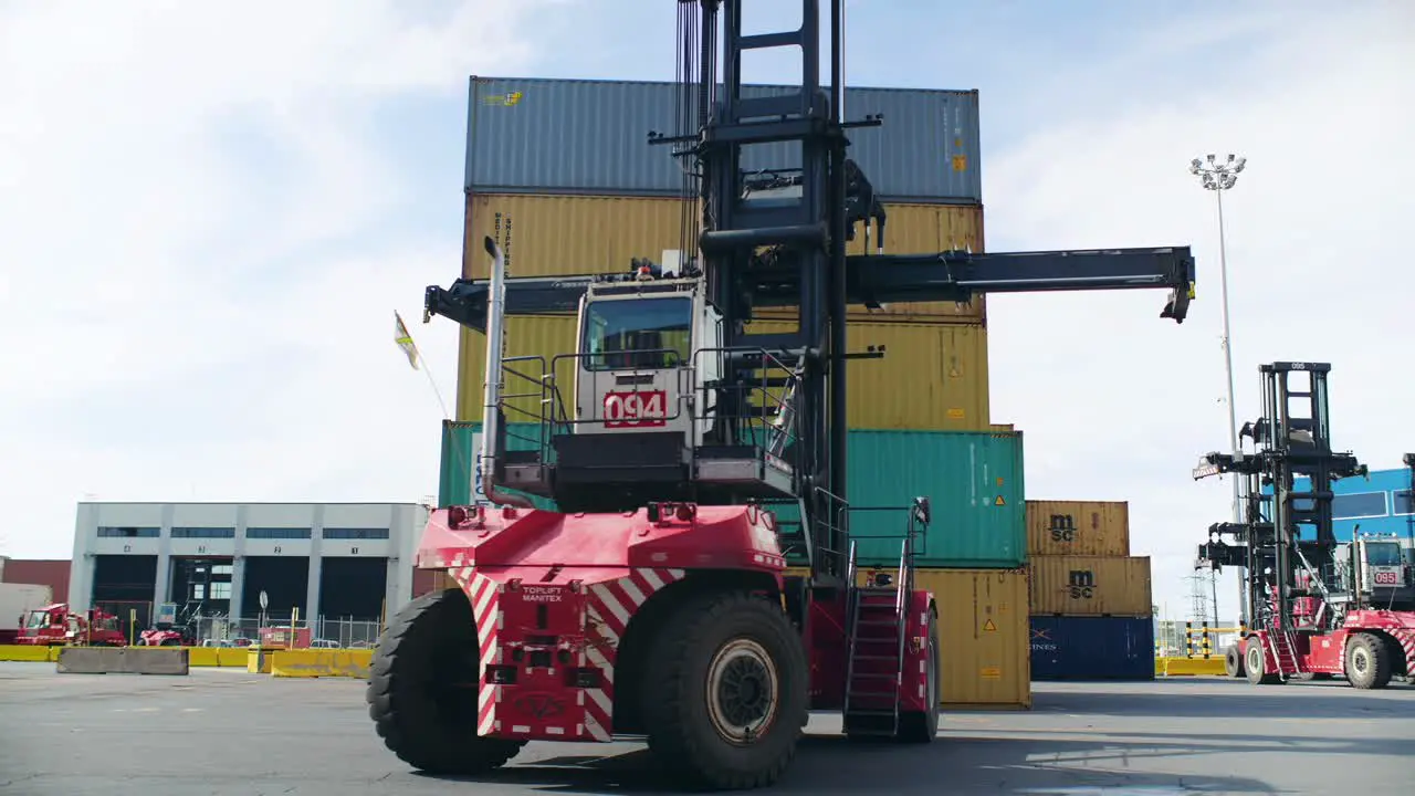 Forklift truck preparing to lift heavy shipping container stacked in Port of Montreal logistics dockyard