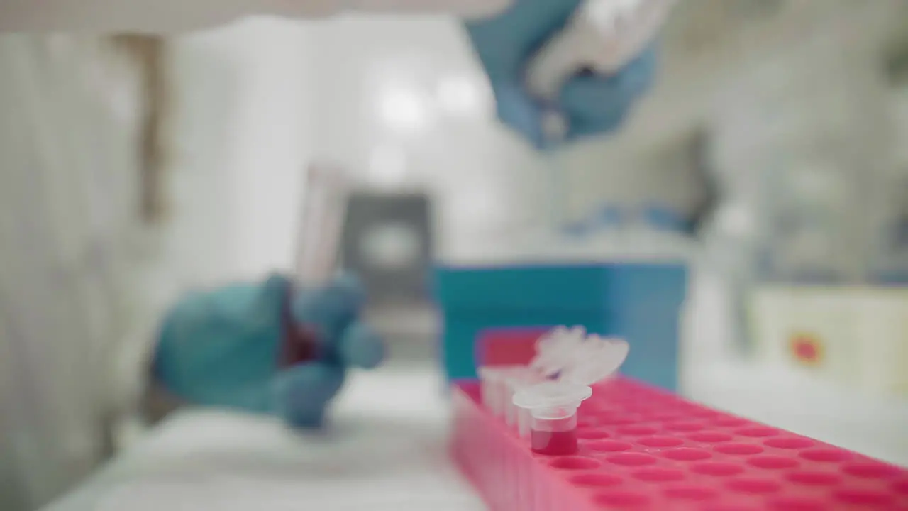 Close-up of a laboratory assistants hand of a woman in a protective suit doing research with blood samples of a virus infected