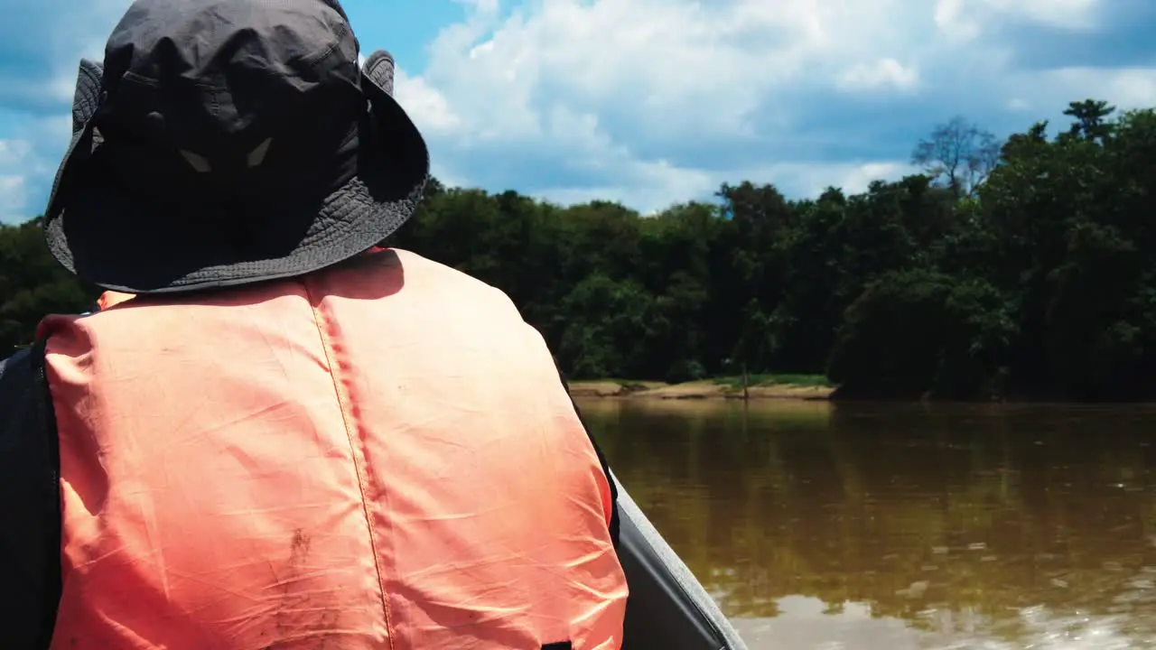 Back View of Scientist-Explorer With Hat and Life Jacket Navigating on Boat Along Kinabatangan River in Malaysia During a Scientific Expedition