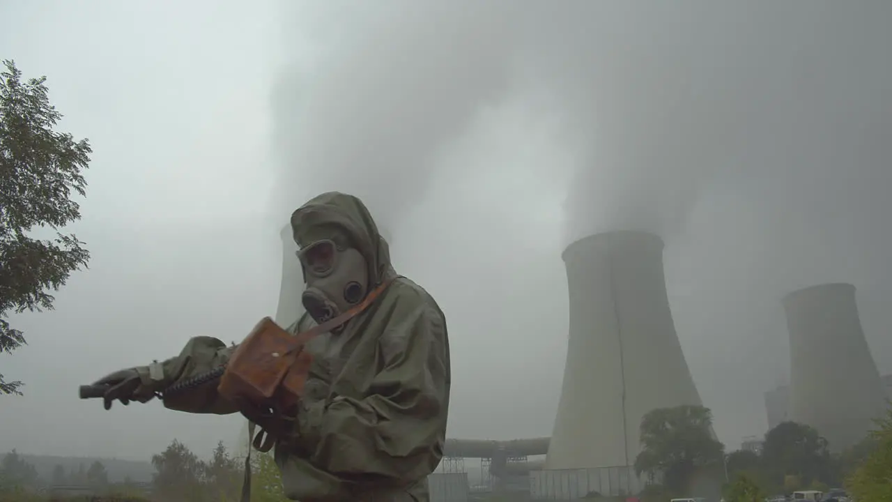 A soldier in a protective suit checks a radiation leak outside the cooling towers of a nuclear reactor