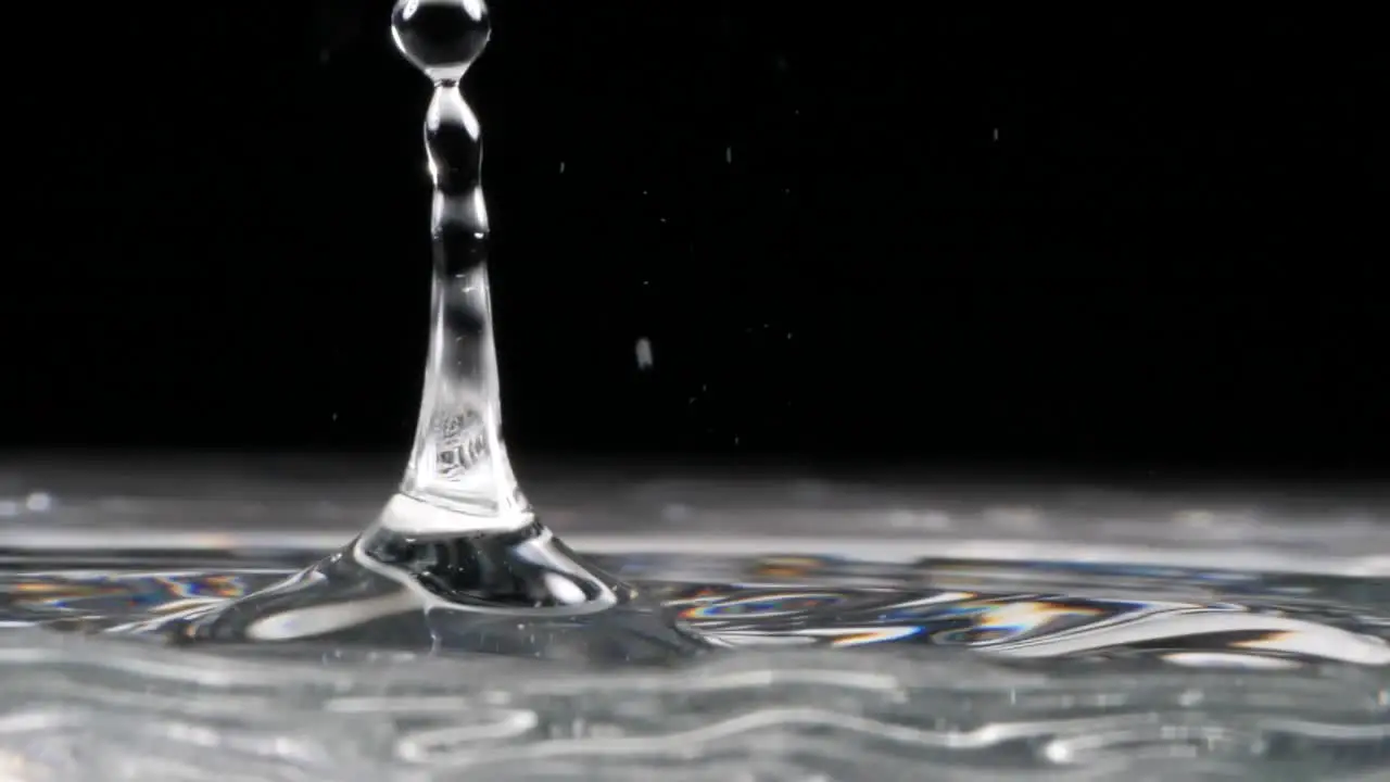 Slow motion crystal droplets fall into water on a black background