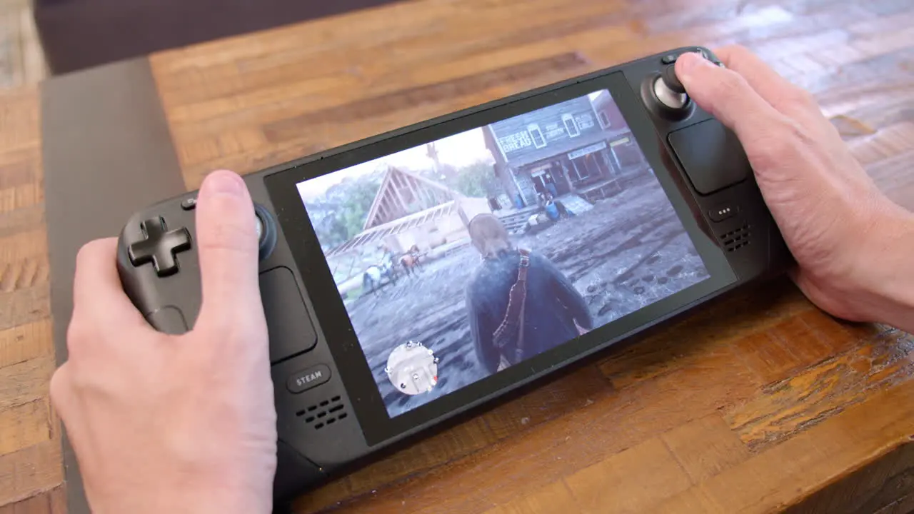 Close-up of playing Red Dead Redemption 2 on a Steam Deck handheld video game system while resting it on a table