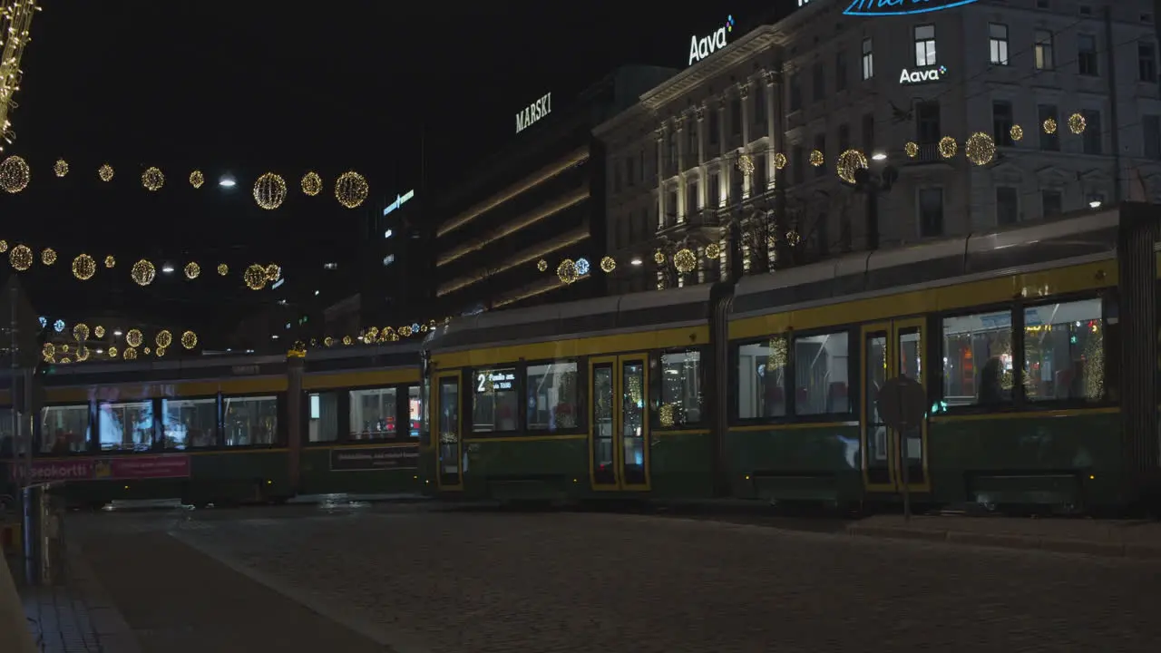 Two trams pass on a street decorated with Christmas lights at night