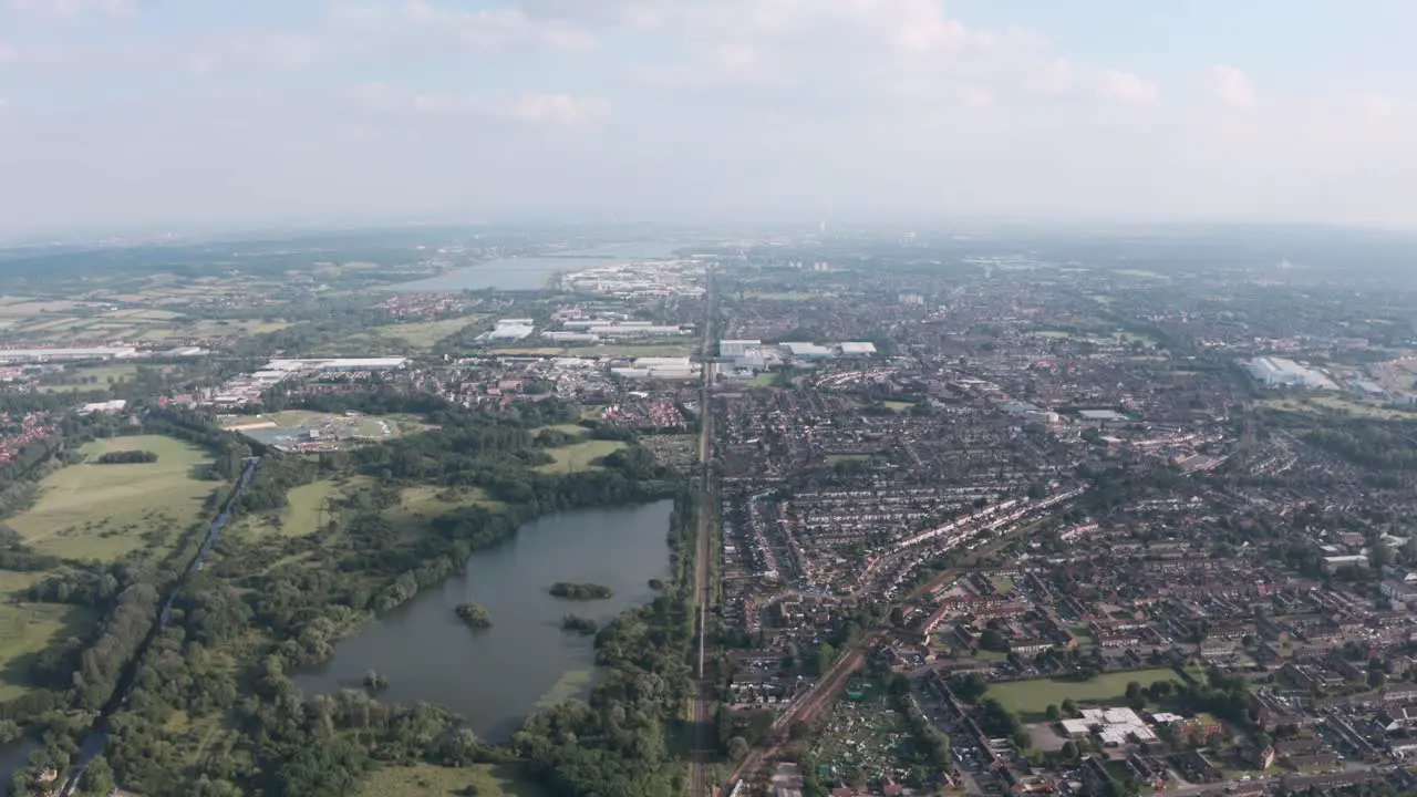 High drone shot of long straight train tracks separating UK town from natural reserve