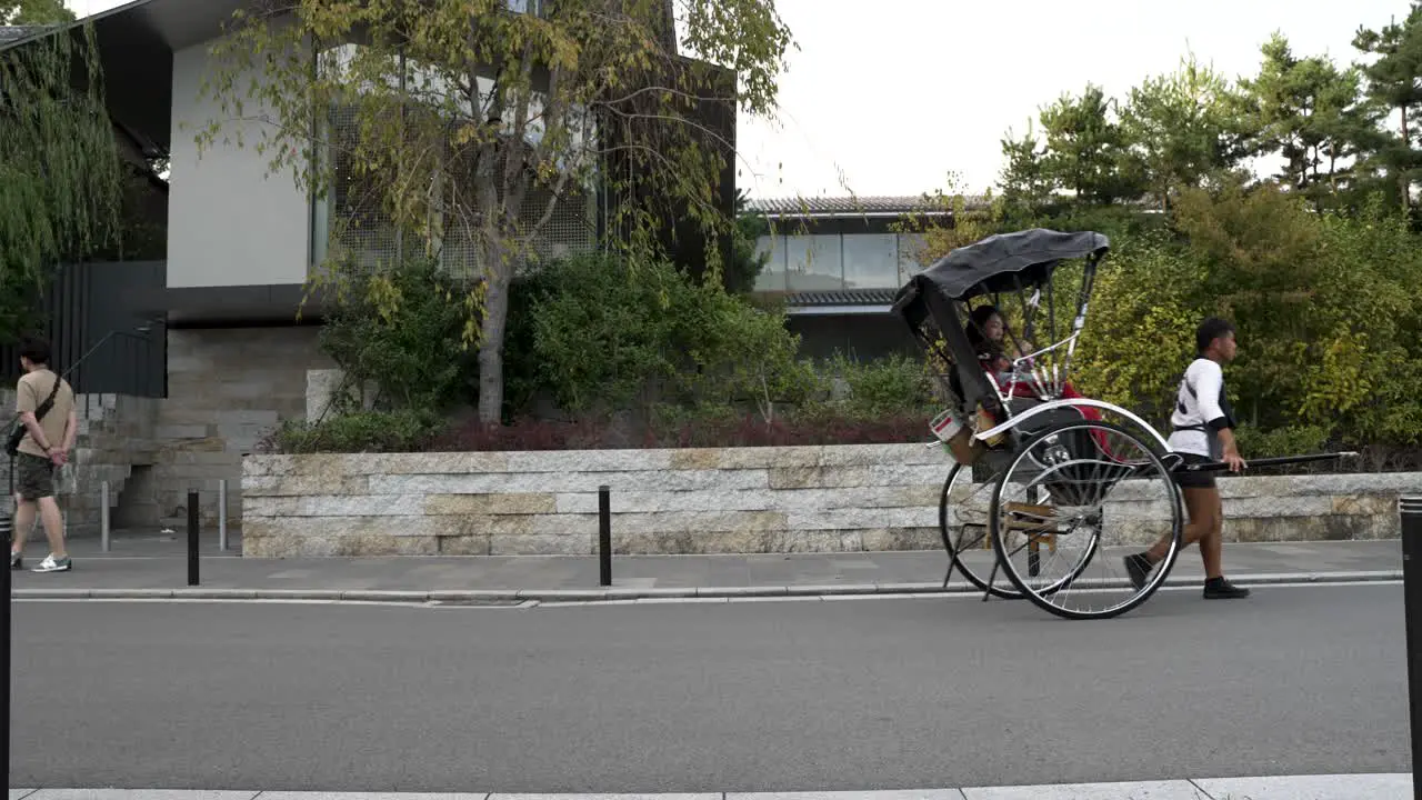 Rickshaw Pulling Tourists Along Road In Arashiyama District Of Kyoto