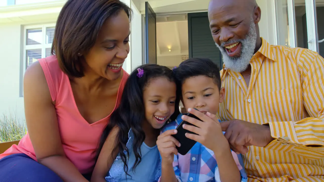 Front view of black family using mobile phone in a comfortable home 4k