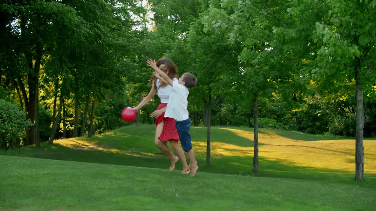 Mother and children playing with ball in meadow Family enjoying time outside