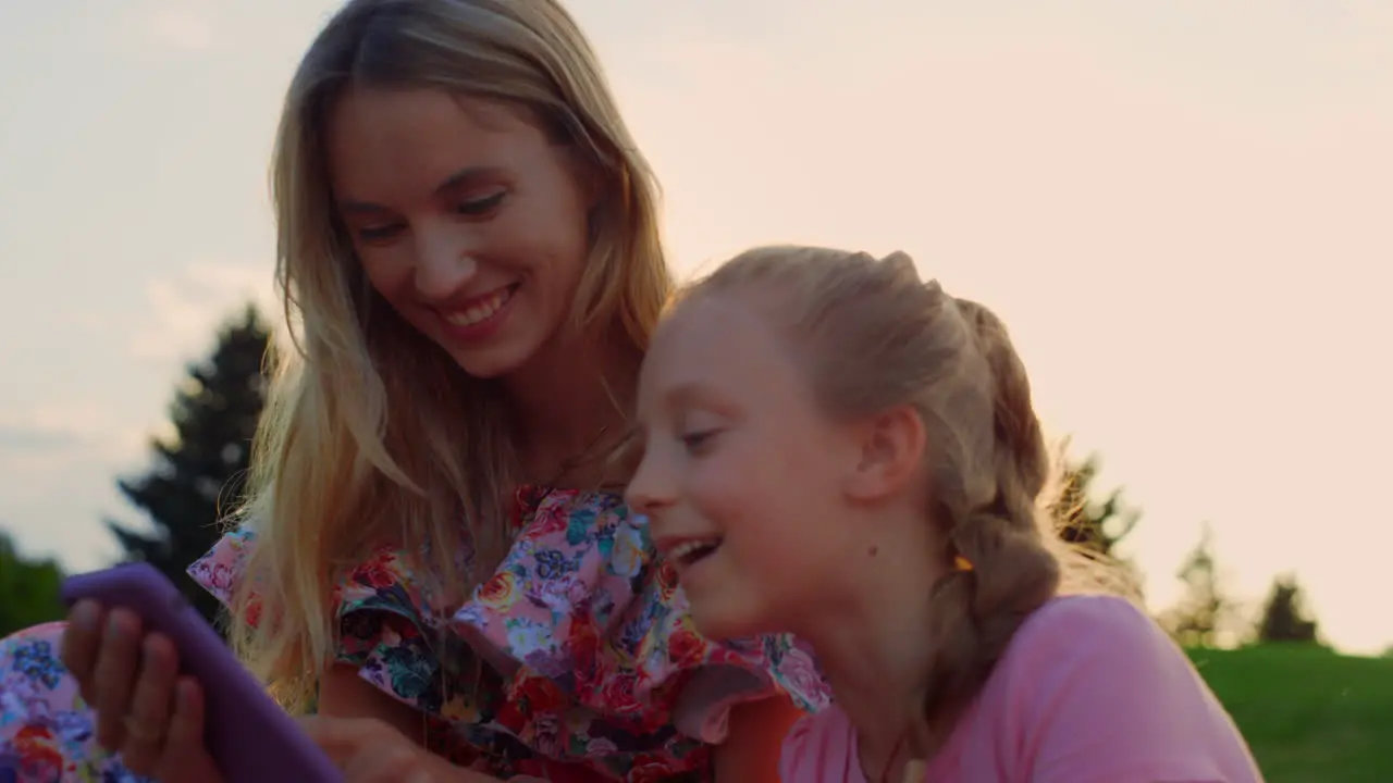 Cheerful family laughing at meadow Woman and girl having fun in city park