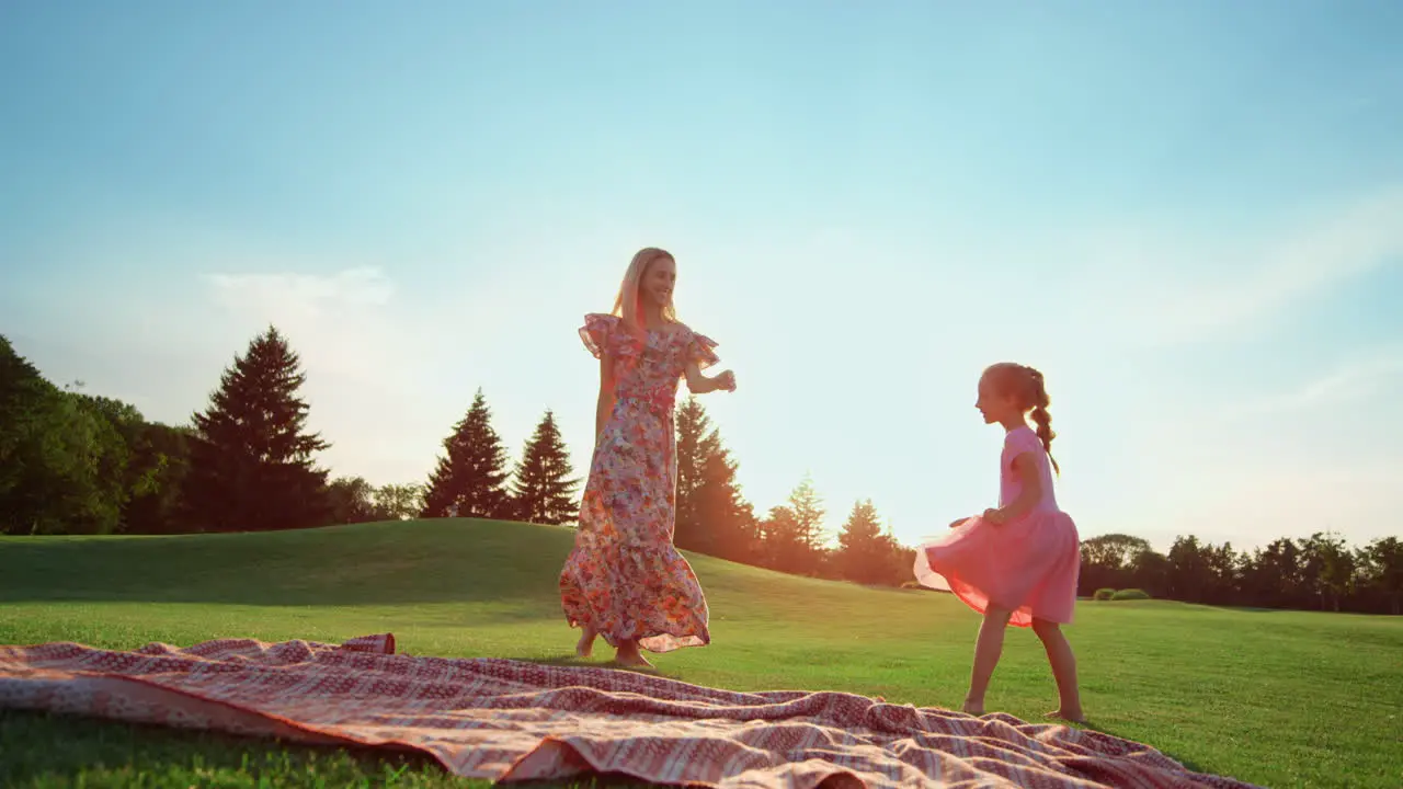 Happy mother dancing with daughter on grass Girl doing cartwheel in park