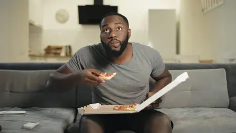 Concentrated man looking at tv screen Happy football fan biting pizza