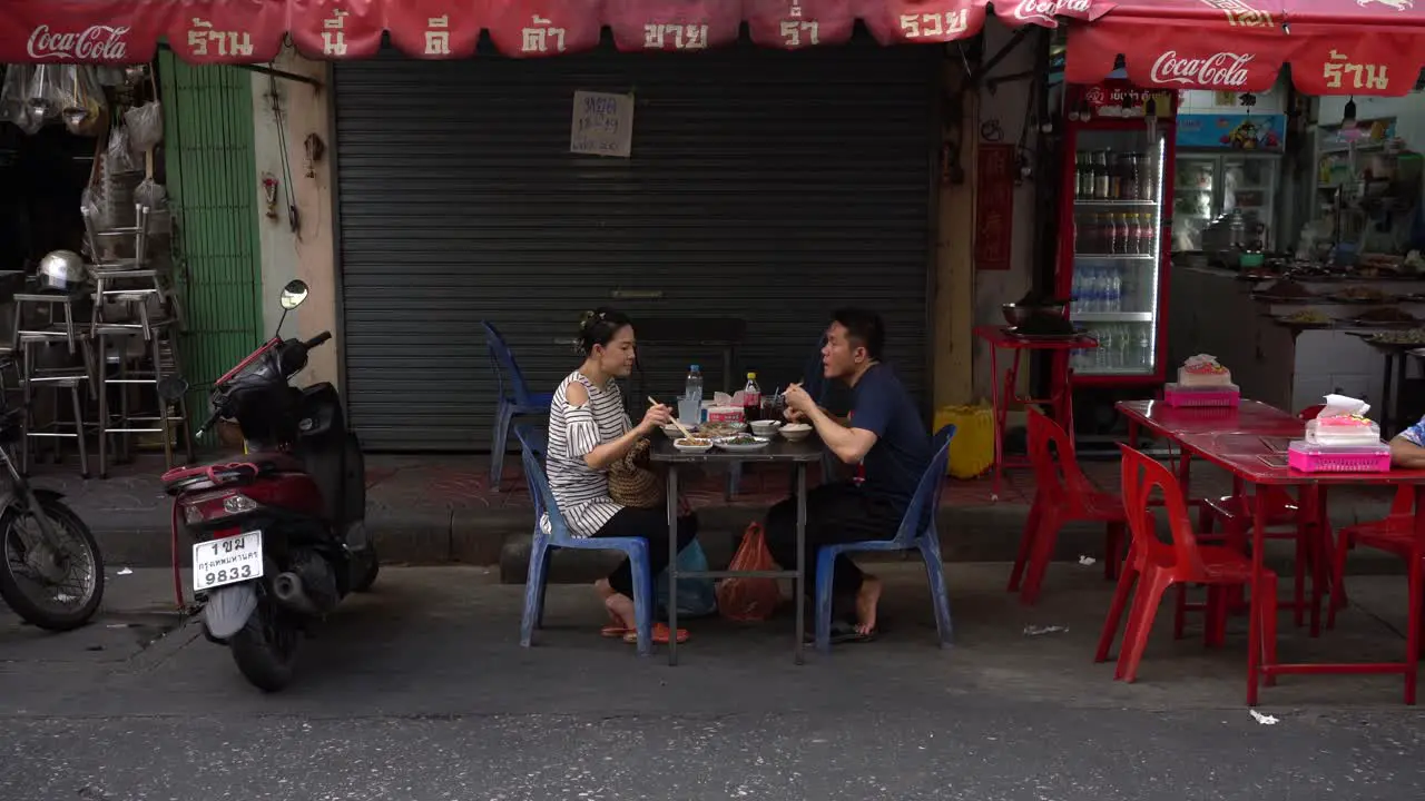 Couple happily dined food on the roadside and chit-chatted in the street restaurants at Yaowarat Chinatown Bangkok Thailand