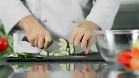 Male chef cutting fresh vegetable Closeup chef hands slicing cucumber