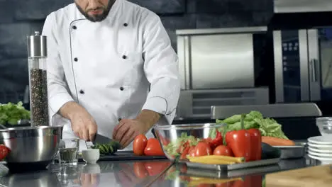 Chef cooking fresh salad at kitchen Closeup male hands cutting cucumber