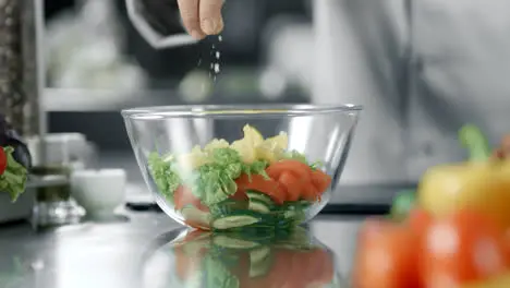 Chef man salting salad at kitchen restaurant Closeup hand salting vegetables