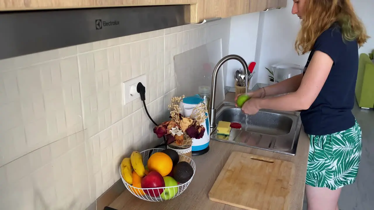 Woman Washing an Apple Over the Sink to Ensure Safe and Clean Eating at Home