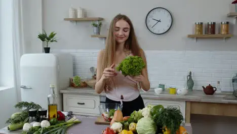 Happy girl dancing having fun and cooking salad with raw vegetables Throwing pieces of lettuce