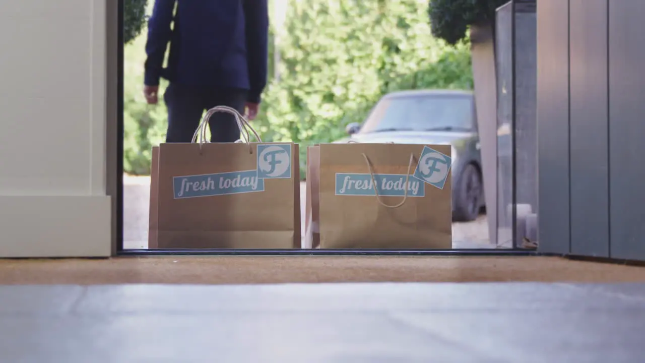 Man Wearing Mask Making Home Delivery Of Takeaway Food To Front Door Of House During Health Pandemic