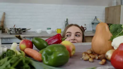 Girl peeping from under the table and stealing fresh apple and eating it Weight loss diet concept