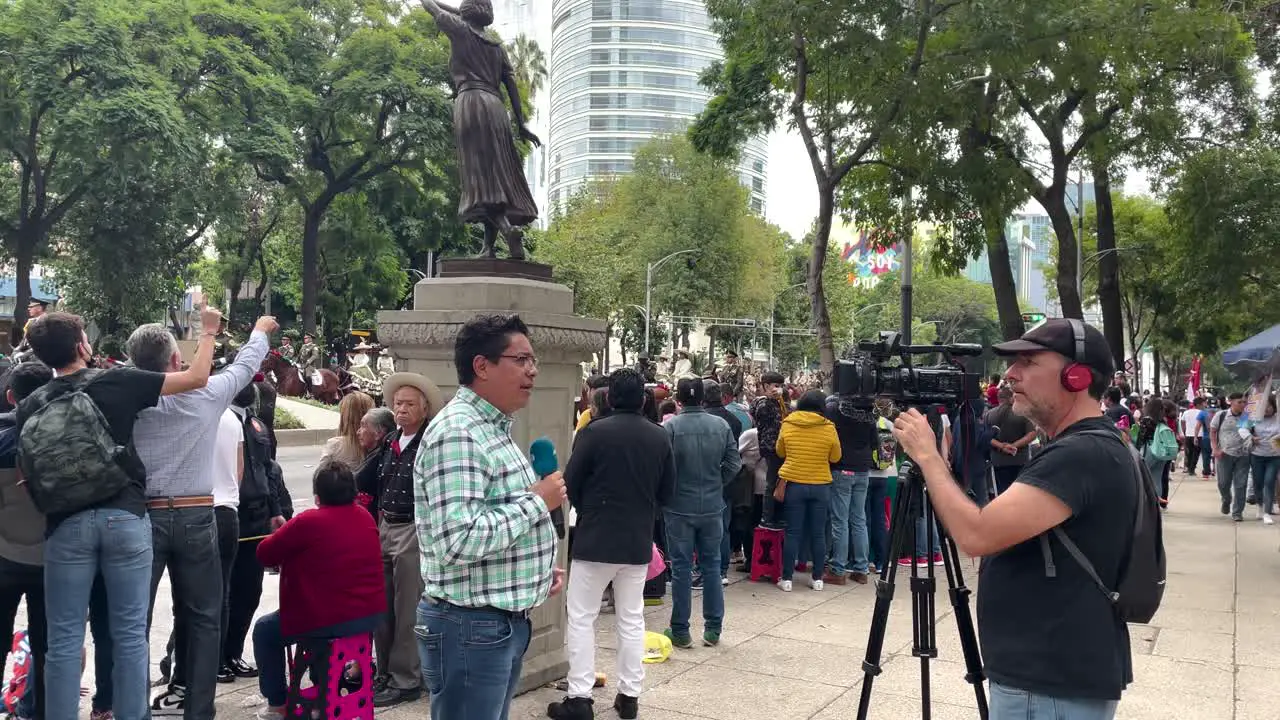 parade shot of a reporter interviewing people during the military parade in mexico city