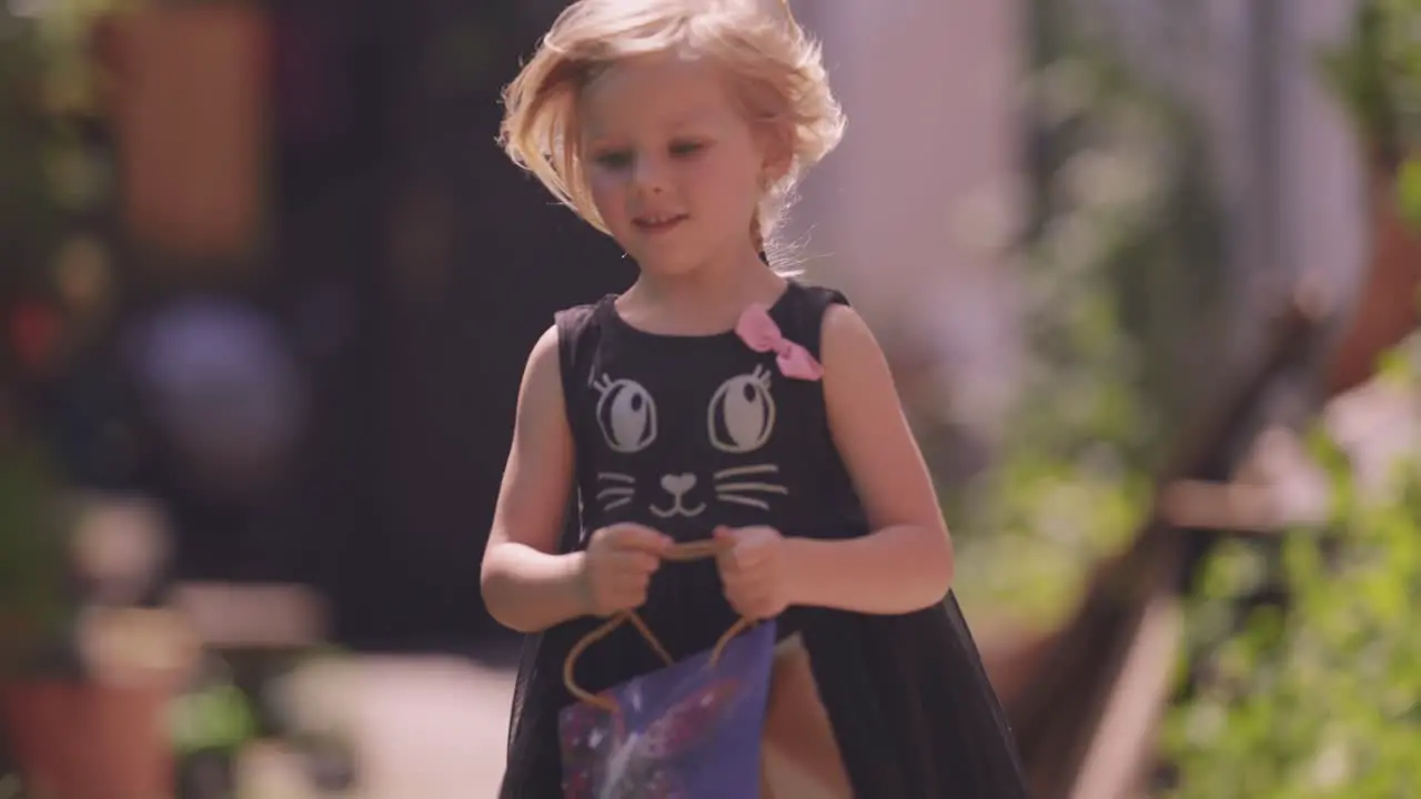 A young fair-haired girl runs joyfully holding a gift bag in her hands